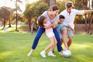 Family Playing Soccer In Park Together